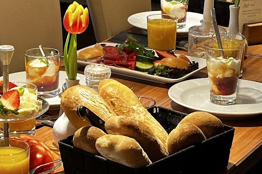 Ein Tisch mit verschiedenen Gerichten, Brötchen, Getränken und einer Tulpe.